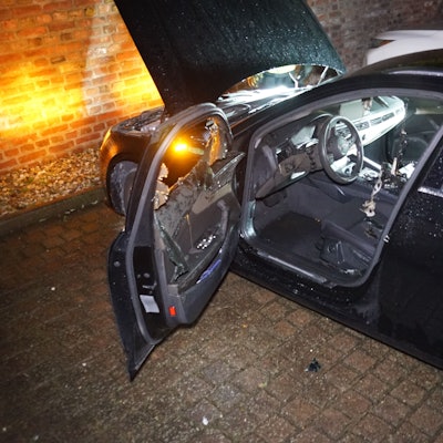 Ein Auto steht mit offener Tür vor einer Wand, der Innenraum ist beschädigt.