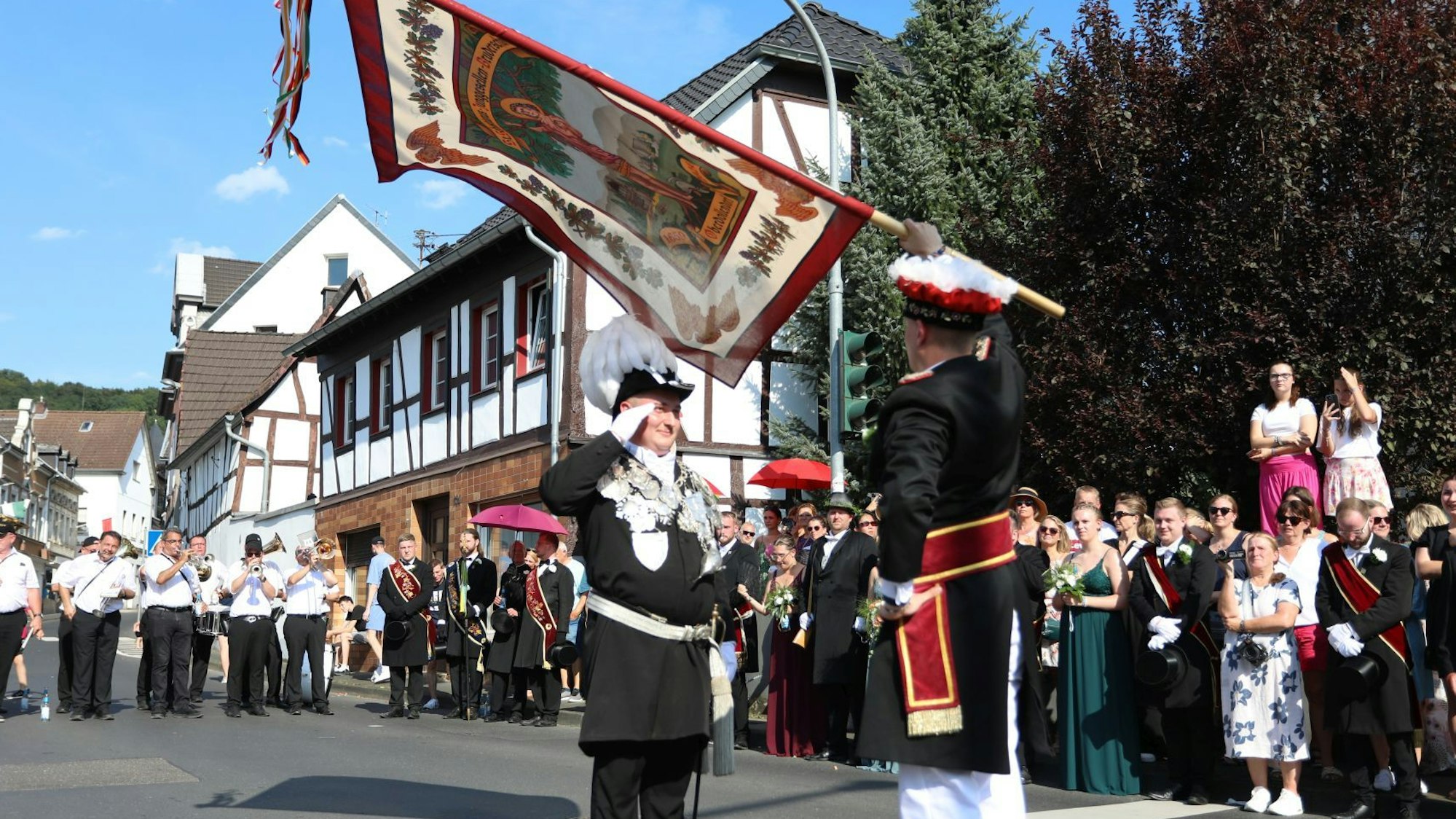 Ein Fahnenschwenker mit dem neuen König, am Straßenrand stehen viele Zuschauer.