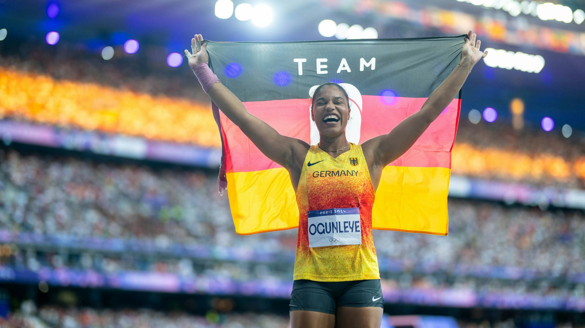 Yemisi Ogunleye hält nach ihrem Gold-Erfolg bei Olympia eine Deutschland-Fahne in die Luft.