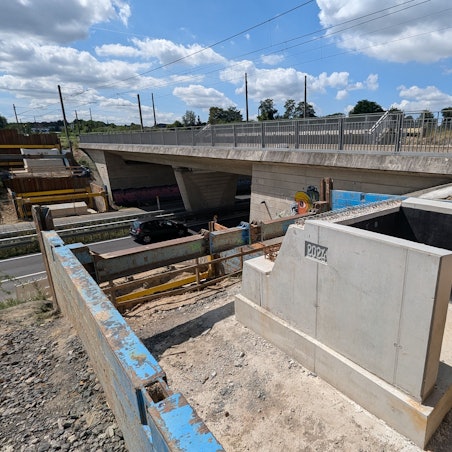 Ein Brückenfundament mit der eingegossenen Jahreszahl 2024 neben einer Brücke über eine vierspurige Straße.