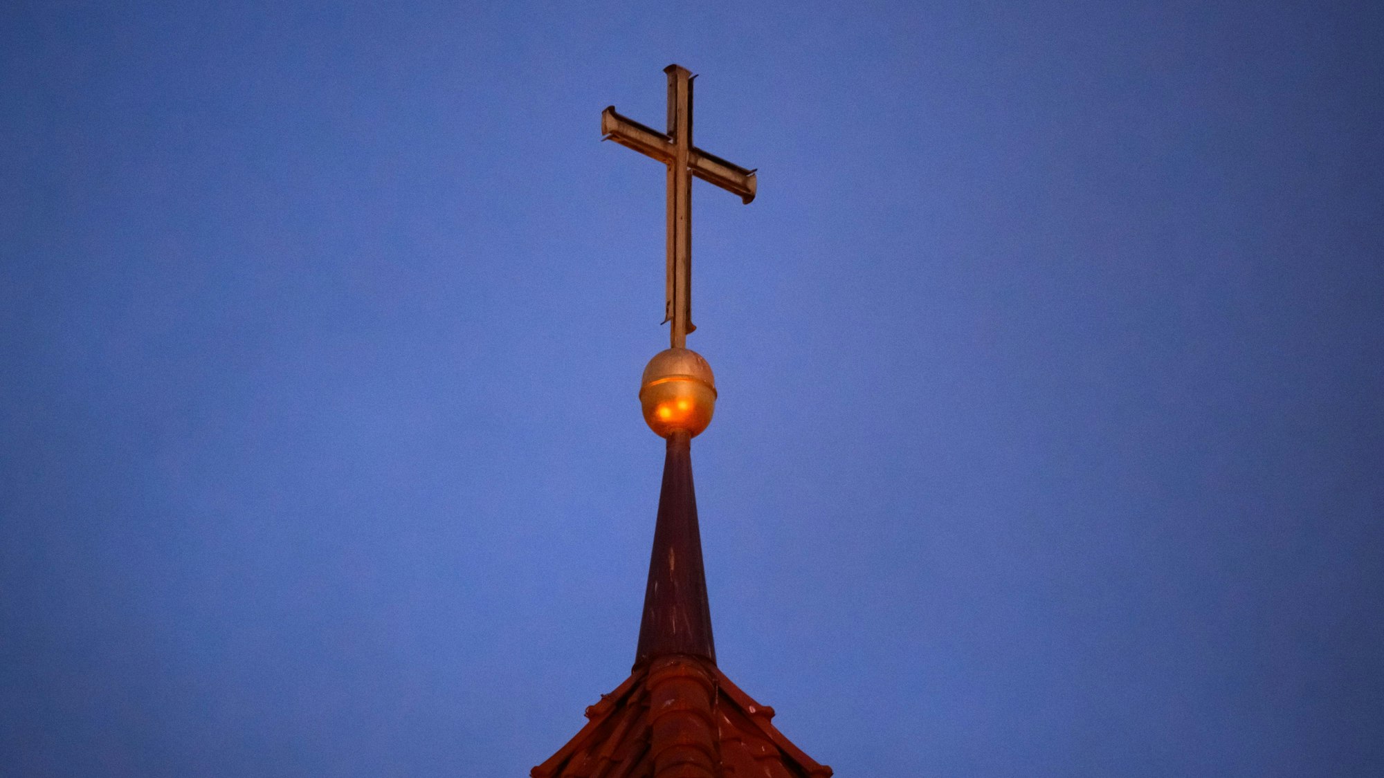 Ein Kreuz steht auf der Kirchturmspitze einer evangelischen Kirche in der Region Hannover. (Symbolbild)