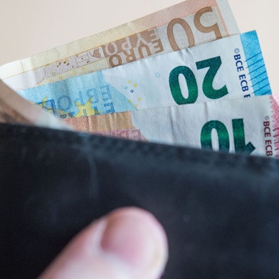 Eine Person hält ein Portemonnaie mit Geld in der Hand. (Symbolbild)