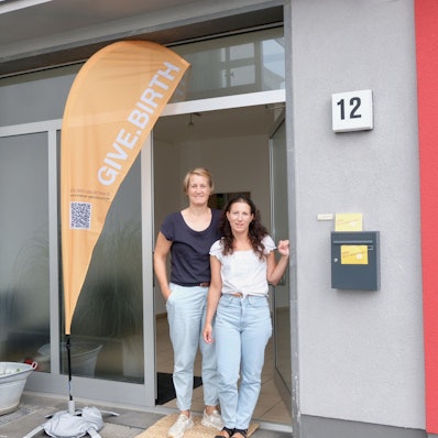 Friederike Hoffmann und Rania Dimtsia (v.l.) im Eingang der neuen Hebammenpraxis am Hermeskeiler Platz.