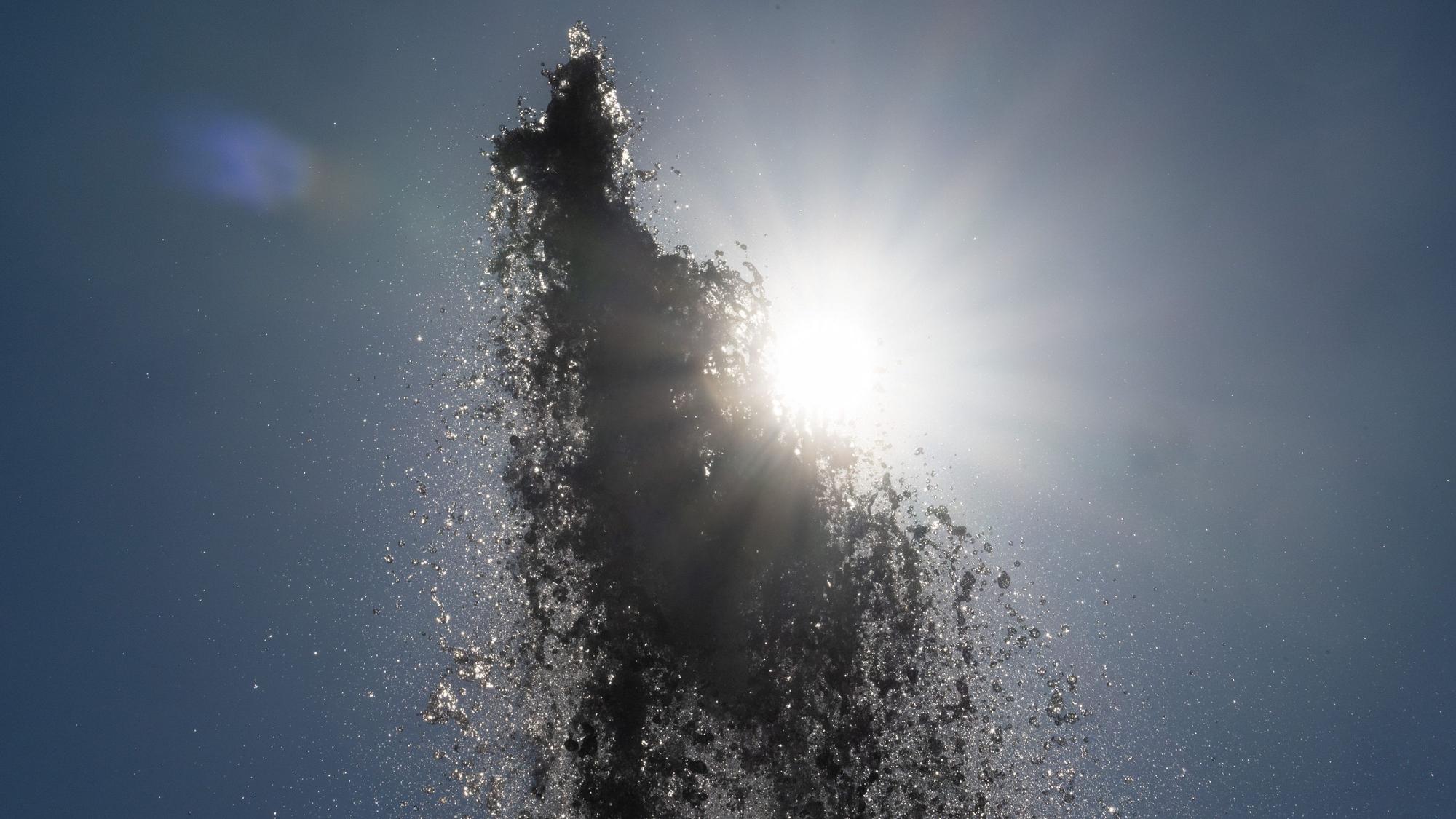 Die Sonne scheint hinter der Wasserfontäne vor der Alten Oper in Frankfurt.