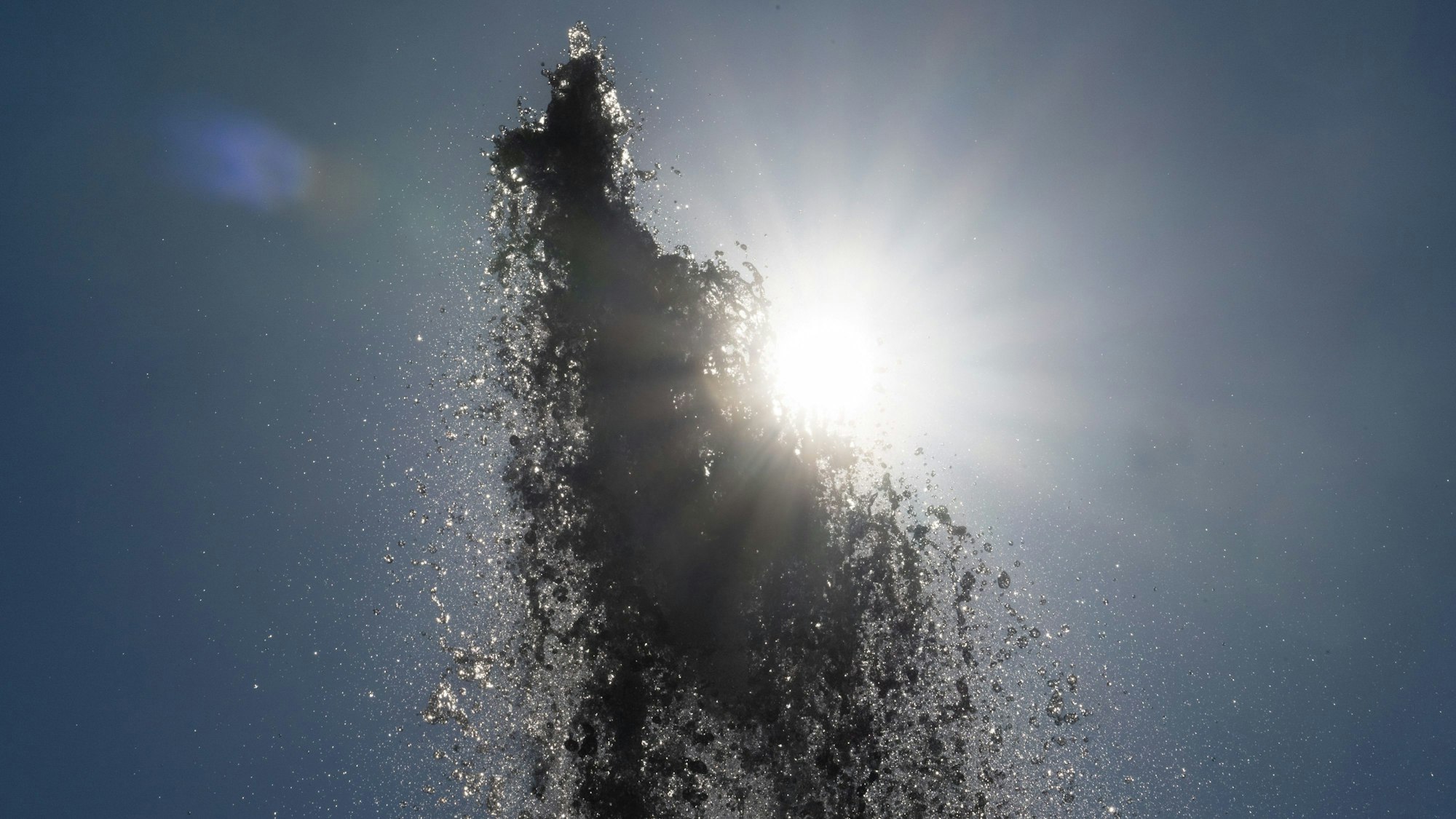 Die Sonne scheint hinter der Wasserfontäne vor der Alten Oper in Frankfurt.
