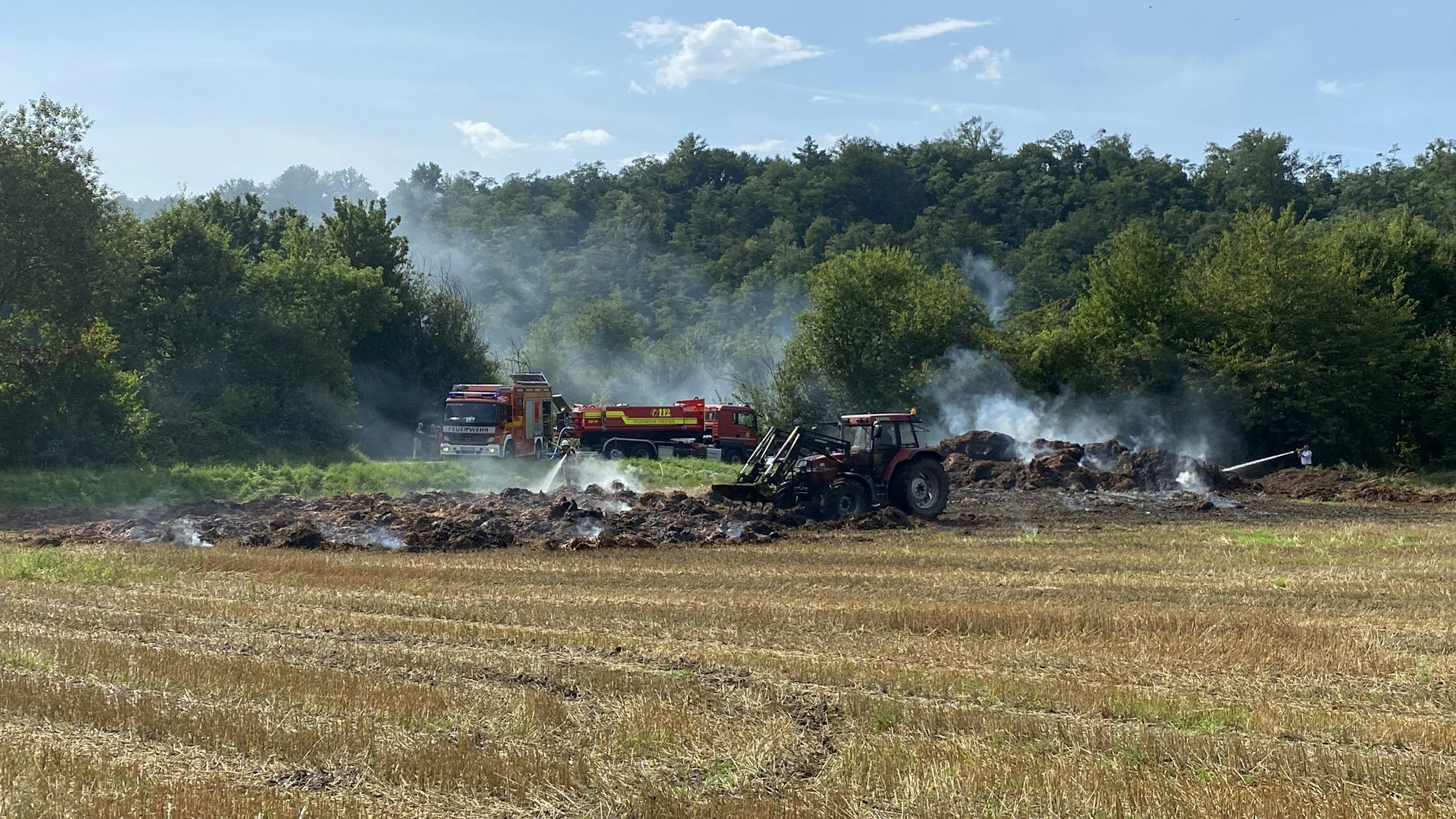 Mit Hilfe eines Traktors wurde der brennende und vor sich hin glimmende Strohstapel auseinandergerissen und gelöscht.