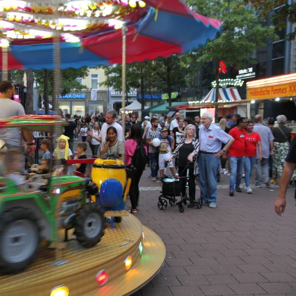 Ein Kinderkarussell auf einem Stadtfest mit einem grünen Traktor