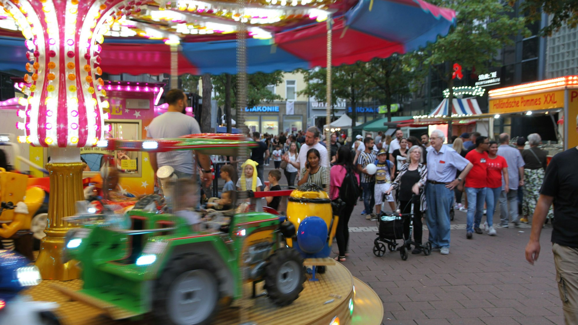 Ein Kinderkarussell auf einem Stadtfest mit einem grünen Traktor