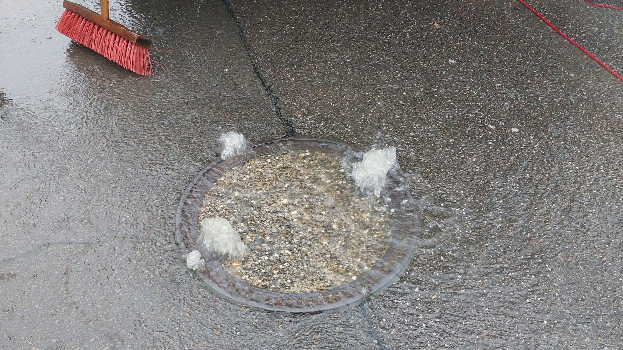 Wasser schießt aus einem Gully.