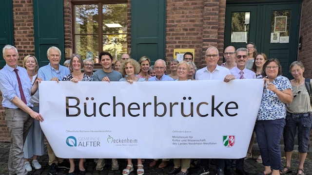 Alle Akteure der Öffentlichen Bücherei Meckenheim-Alfter zeigen ein Plakat mit dem neuen Namen Bücherbrücke.