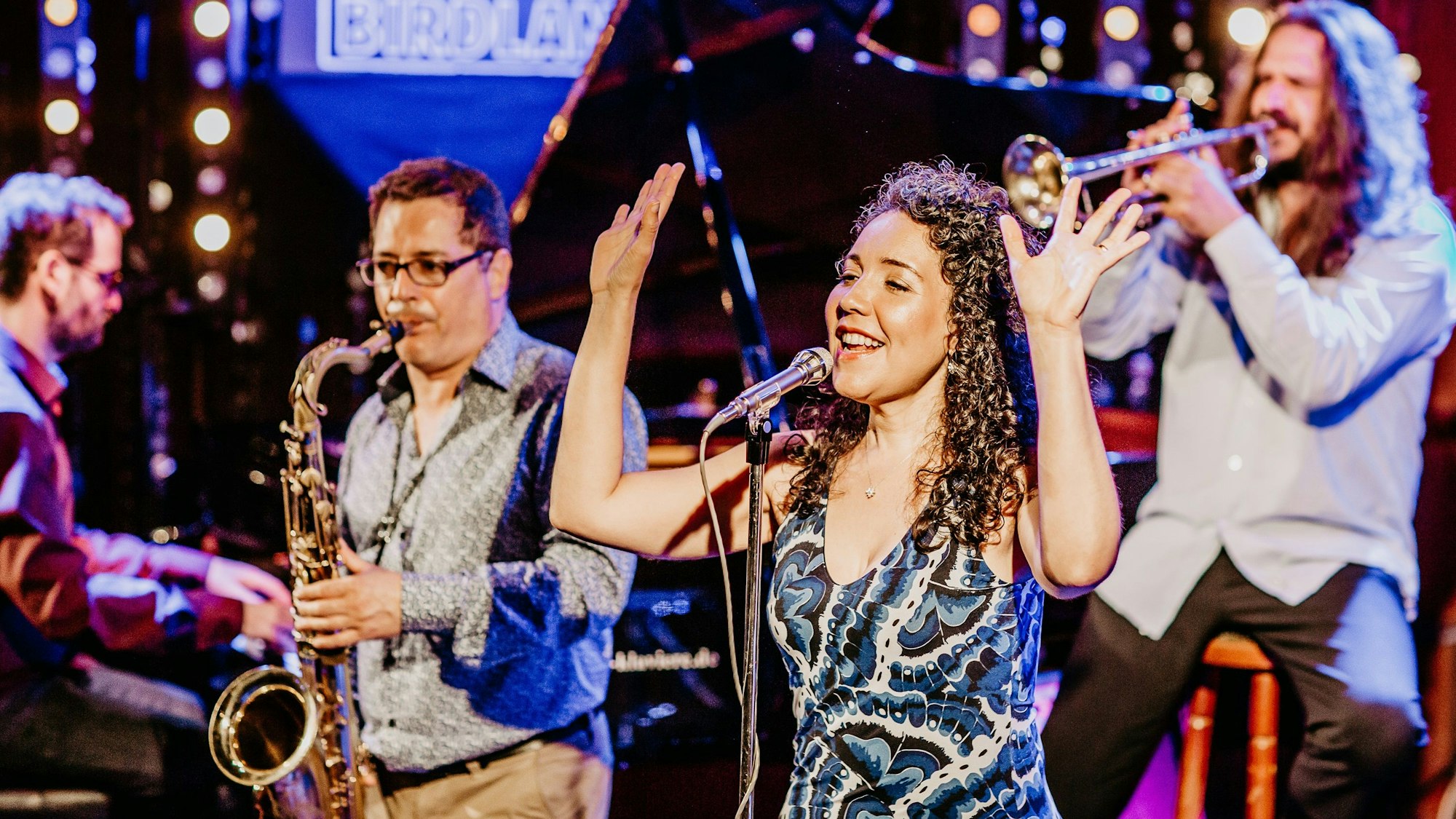 Drei Musiker und eine Sängerin bei einem Auftritt.