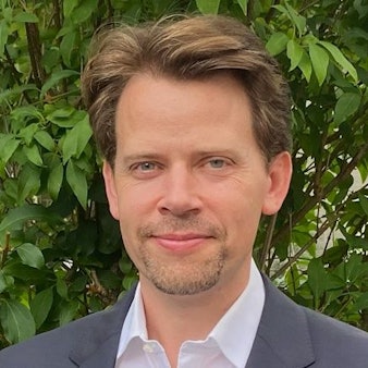 Arne von Boetticher (41) aus Leichlingen steht vor eine grünen Hecke.