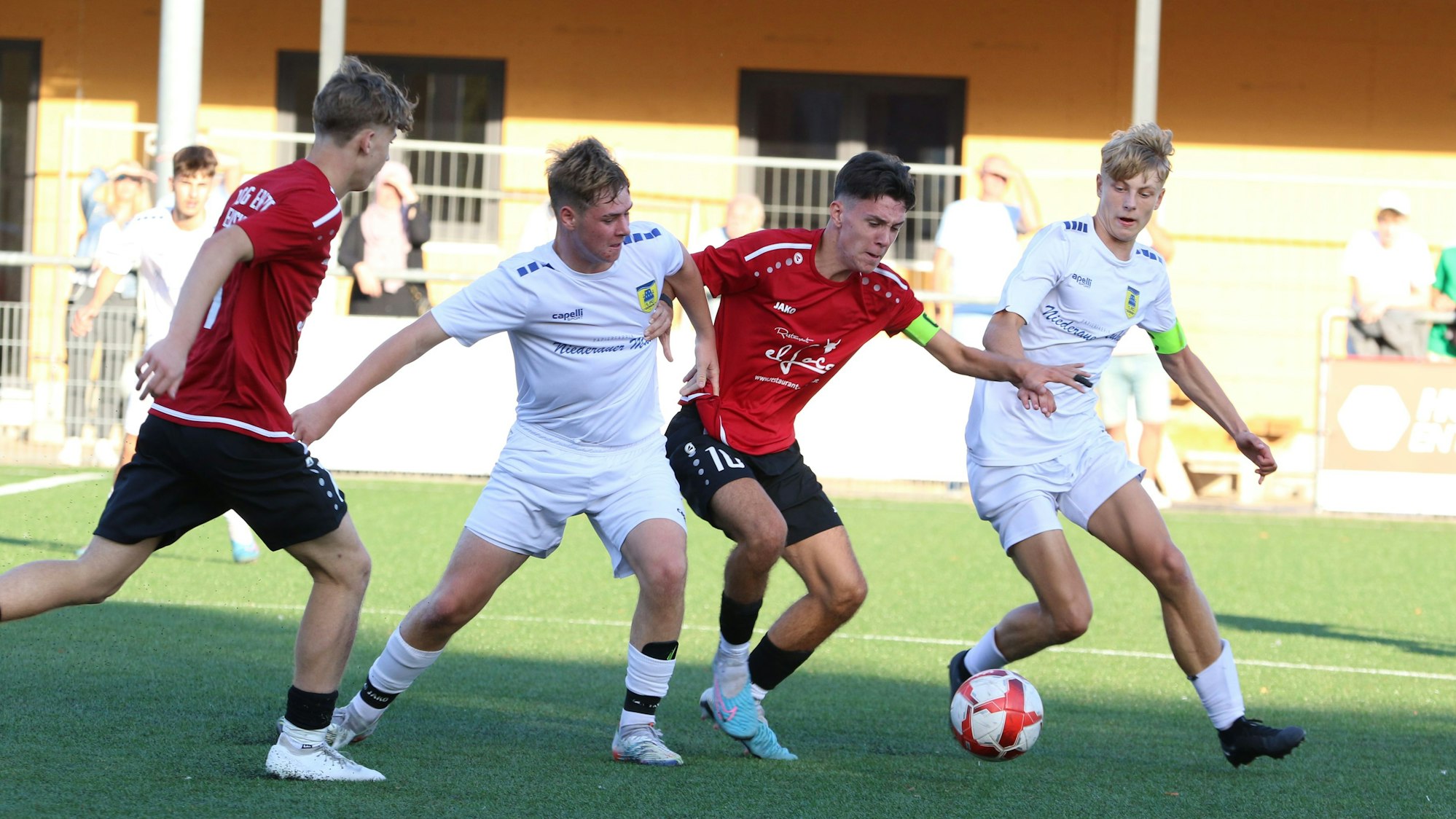 Der Kapitän der JSG Erft 01 hat den Ball und wehrt zwei Dürener Gegenspieler ab.