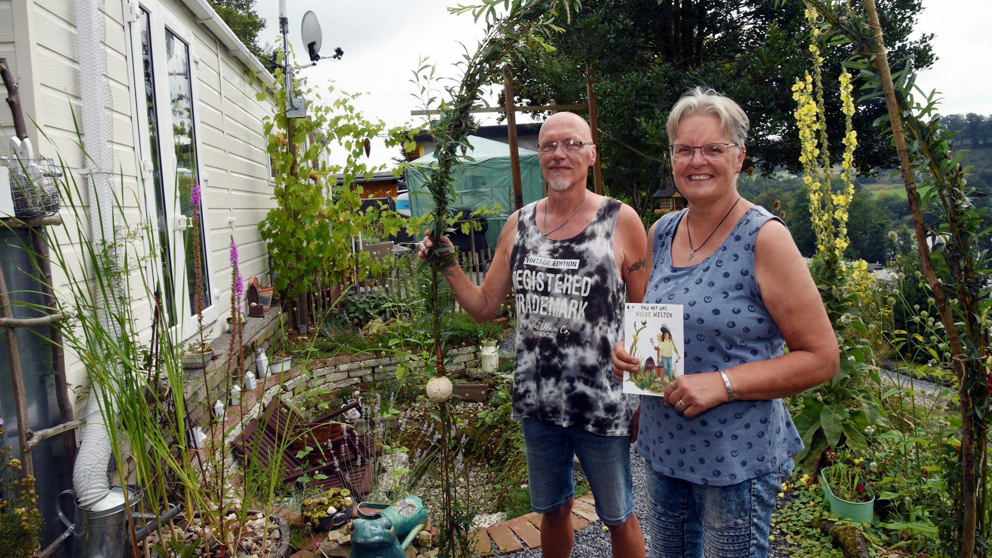 Das Foto zeigt den Naturgarten mit dem Ehepaar Corinna und Andreas Herrmann.