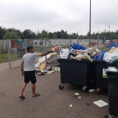 Ein Mann versucht, eine Plastikflasche in übervollen Müllcontainern vor einer Flüchtlingsunterkunft zu entsorgen.