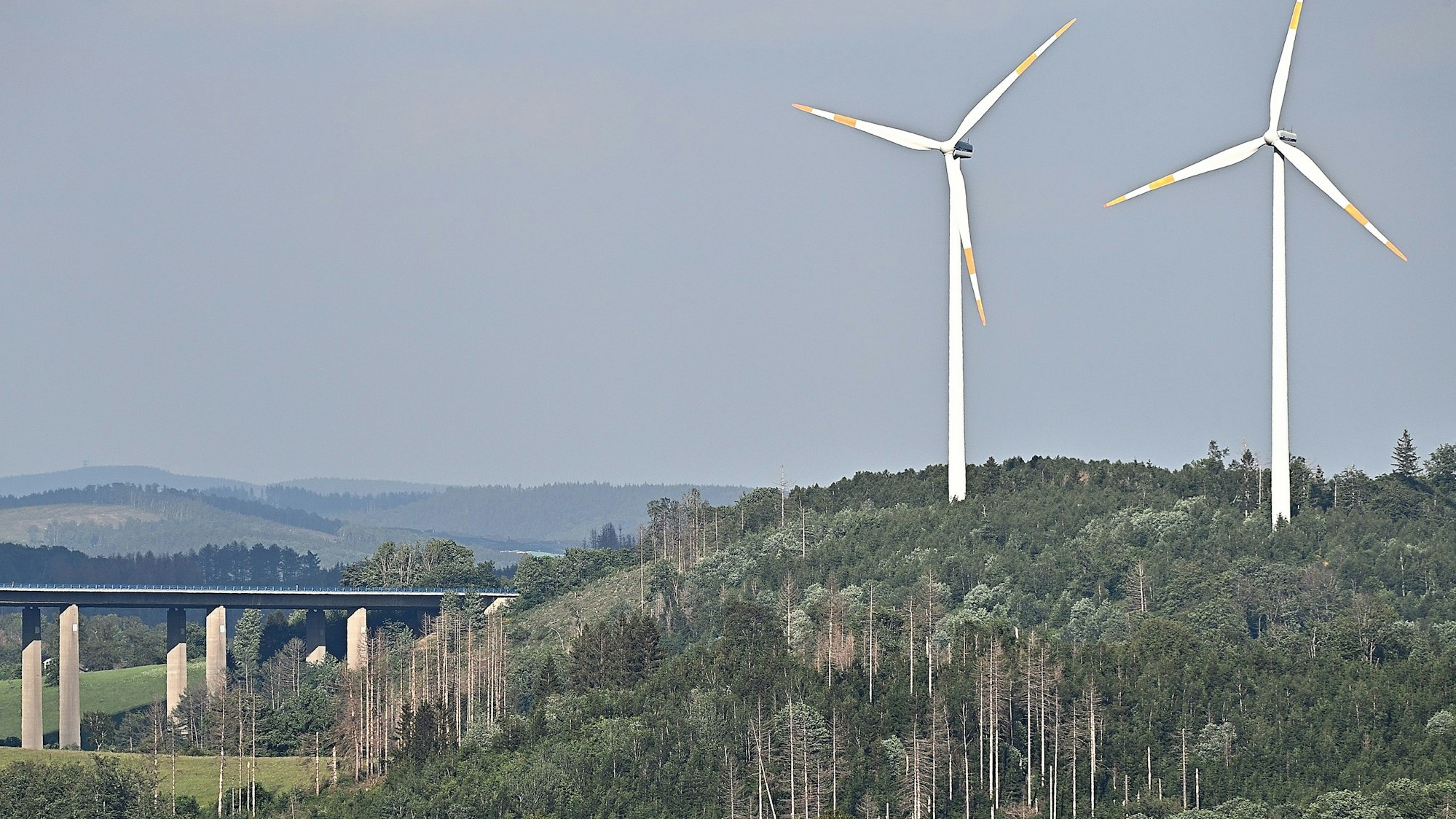 Zwei Windräder überragen in einem Waldgebiet bei Gummersbach-Piene deutlich die Wipfel der Bäume.