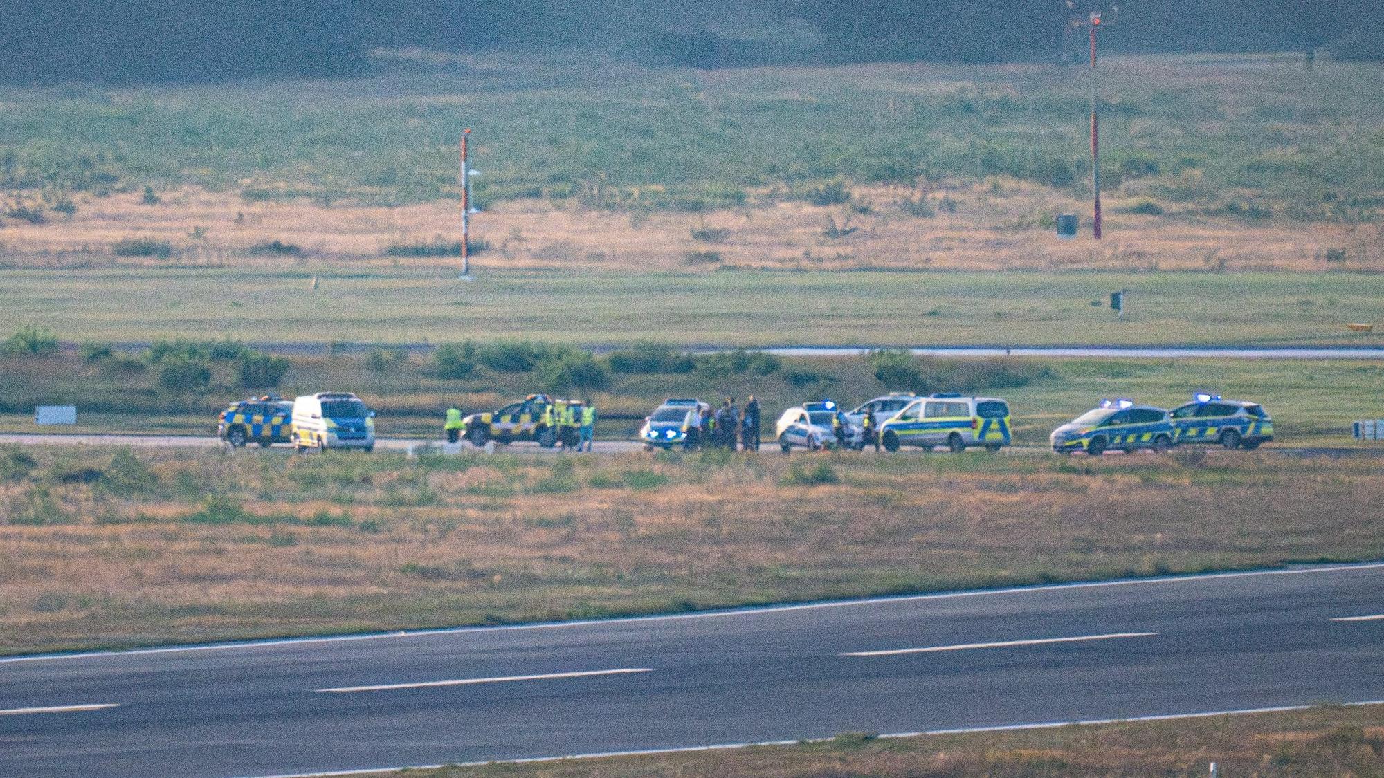 15.08.2024, Nordrhein-Westfalen, Köln: Polizeifahrzeuge und ein Follow-Me Wagen des Flughafen Köln-Bonn stehen auf einer Rollbahn.