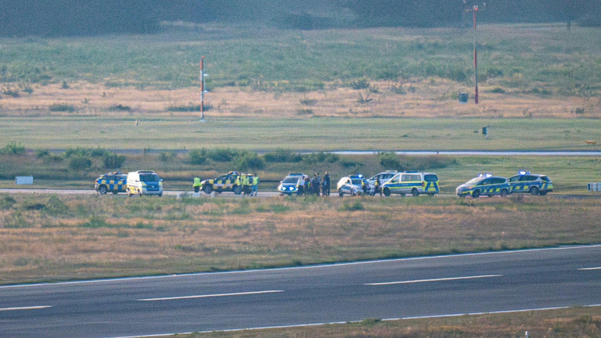 15.08.2024, Nordrhein-Westfalen, Köln: Polizeifahrzeuge und ein Follow-Me Wagen des Flughafen Köln-Bonn stehen auf einer Rollbahn.