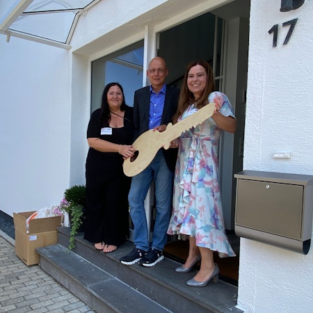Gruppenleiterin Alexandra Blömeling, Stefan Sudek-Wehr und Sarah Eichhorst (v.l.) bei der symbolischen Schlüsselübergabe mit einem großen Holzschlüssel.