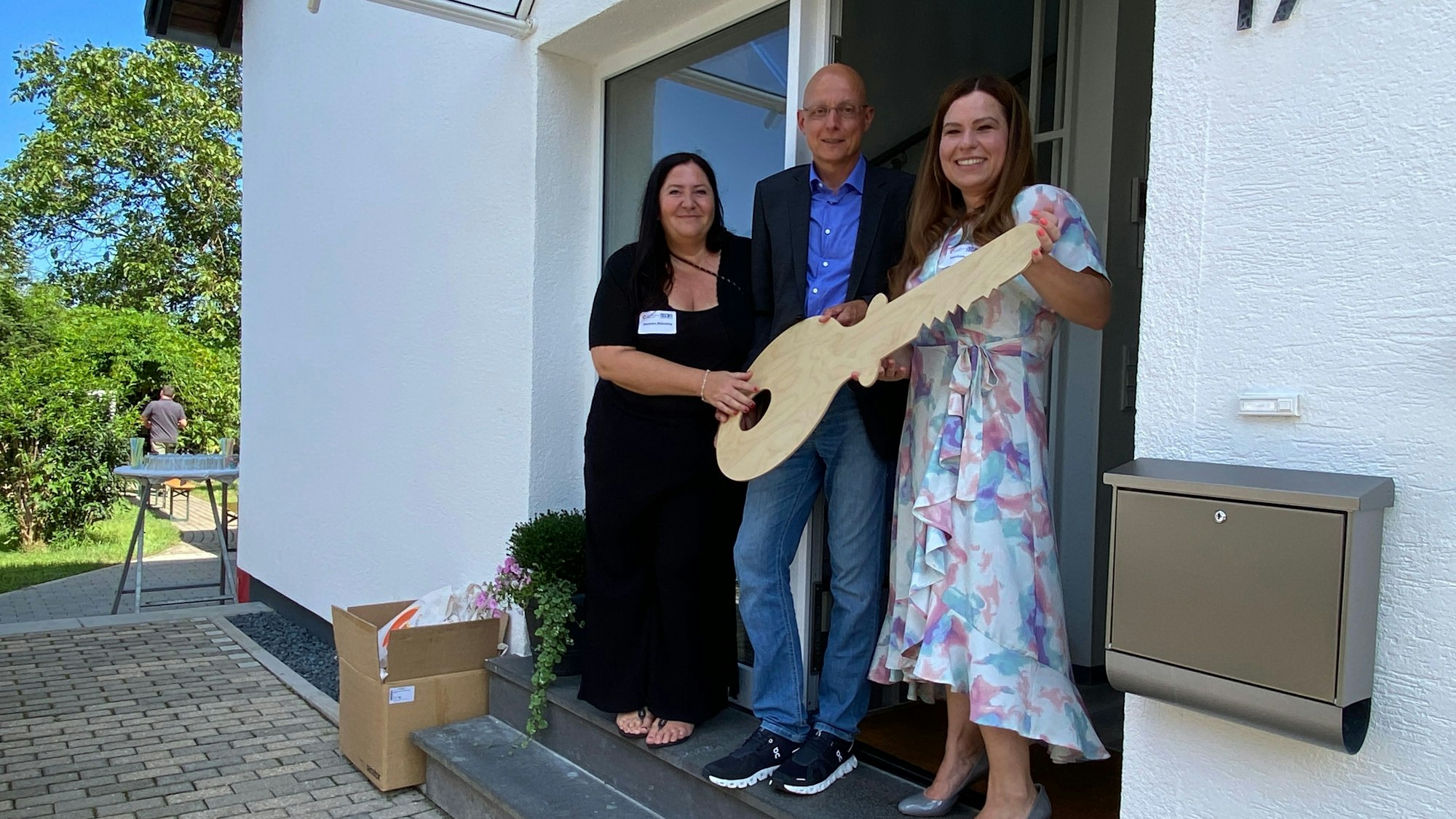 Gruppenleiterin Alexandra Blömeling, Stefan Sudek-Wehr und Sarah Eichhorst (v.l.) bei der symbolischen Schlüsselübergabe mit einem großen Holzschlüssel.