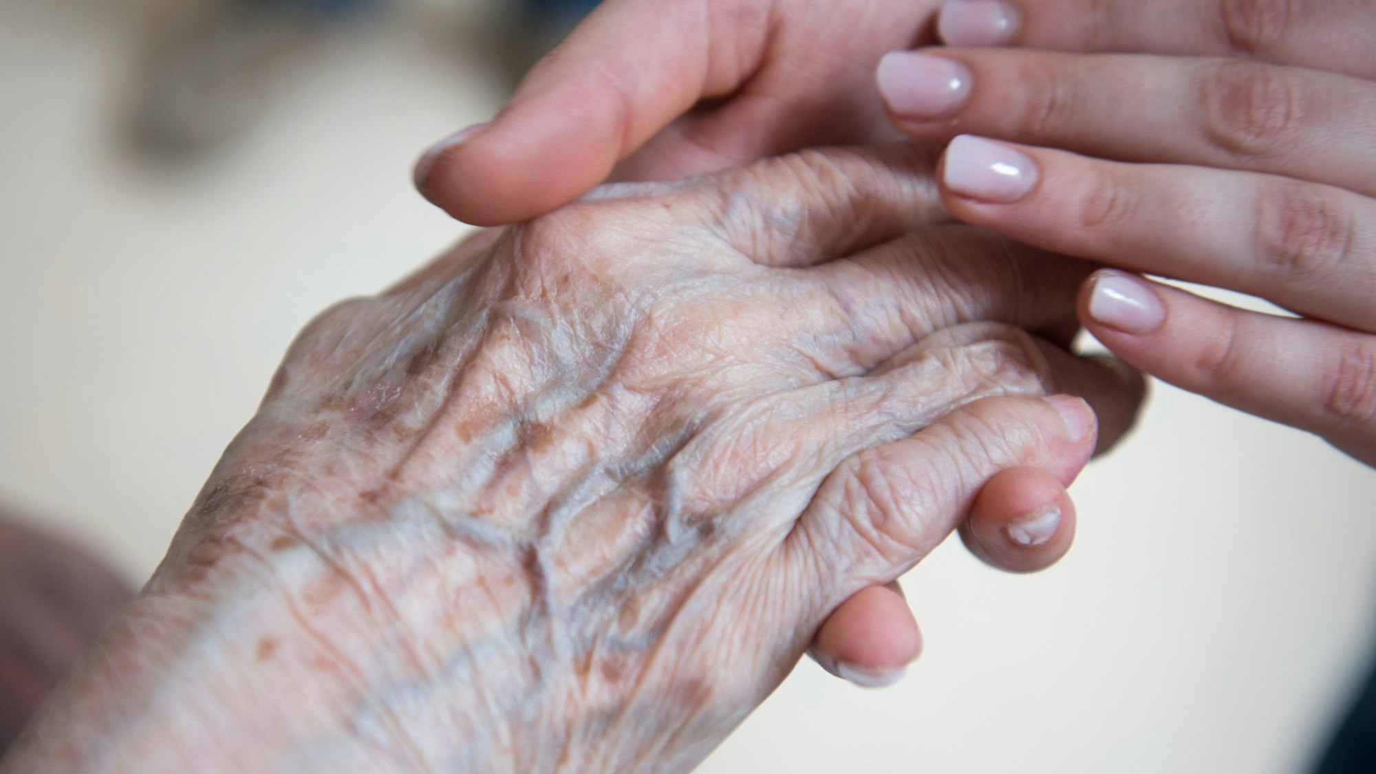 Eine Pflegerin hält die Hand einer Bewohnerin in einem Seniorenzentrum.