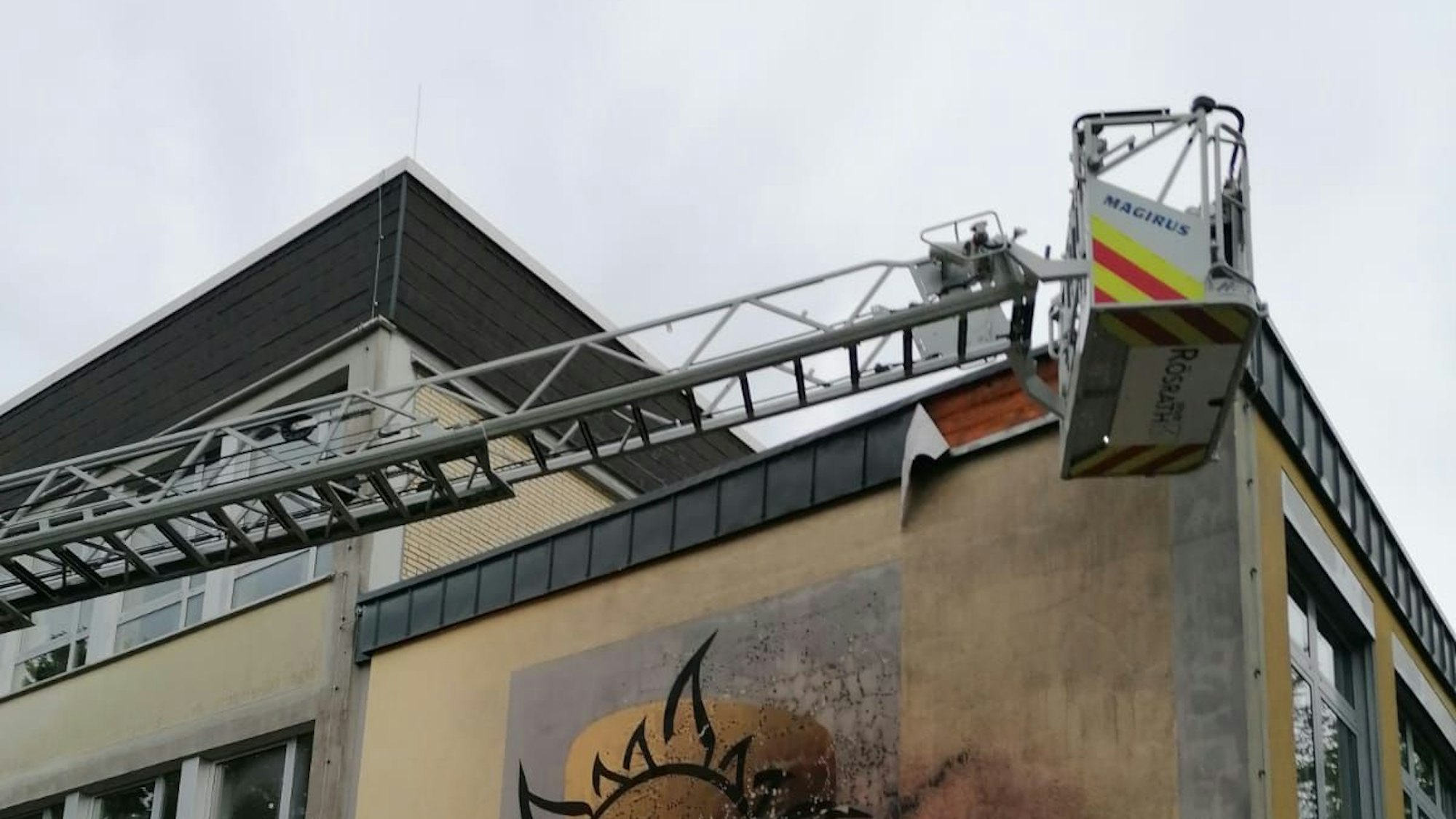 Der Korb einer Drehleiter ist am Dach der Katholischen Grundschule in Immekeppel psoitioniert.