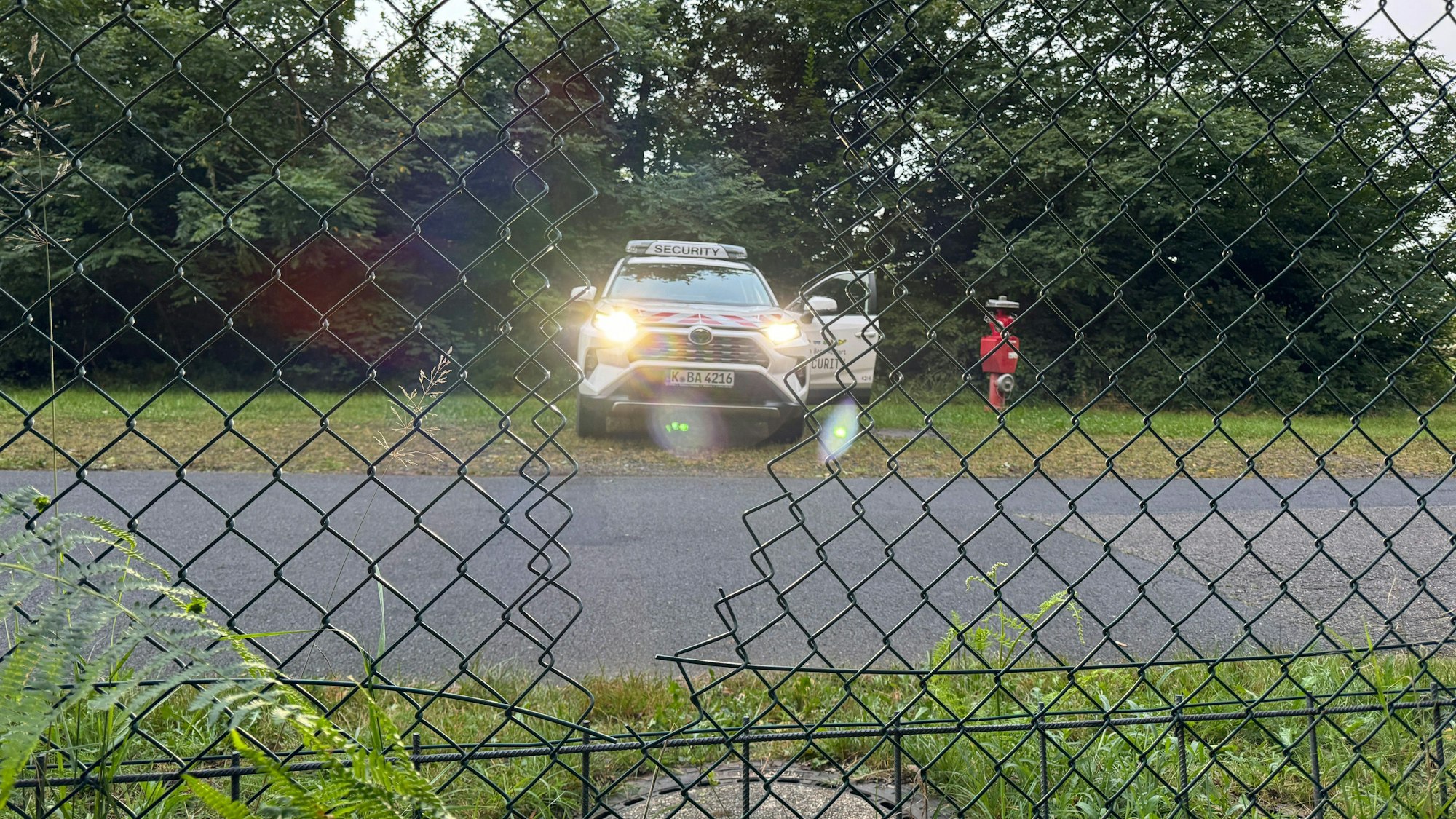 15.08.2024, Nordrhein-Westfalen, Köln: Ein Auto der Flughafensicherheit des Flughafen Köln-Bonn steht hinter dem Zaun des Flughafens.