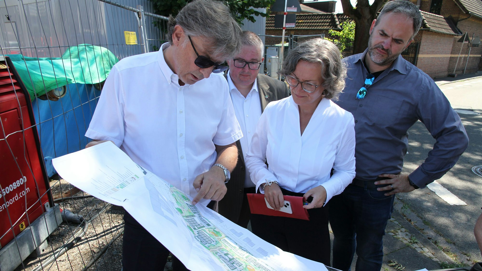 Drei Männer und eine Frau mit einem Bauplan