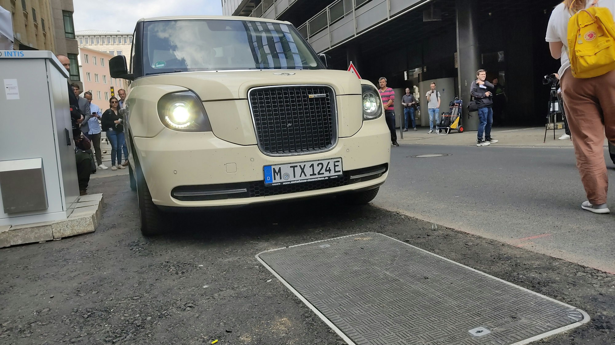 Ein elektrisches London-Taxi steht in der Dompropst-Ketzer-Straße am Kölner Hauptbahnhof vor einer induktiven Ladeplatte.