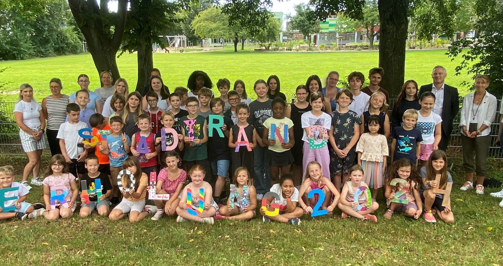 Kinder halten die Buchstaben "Stadtranderholung" hoch.