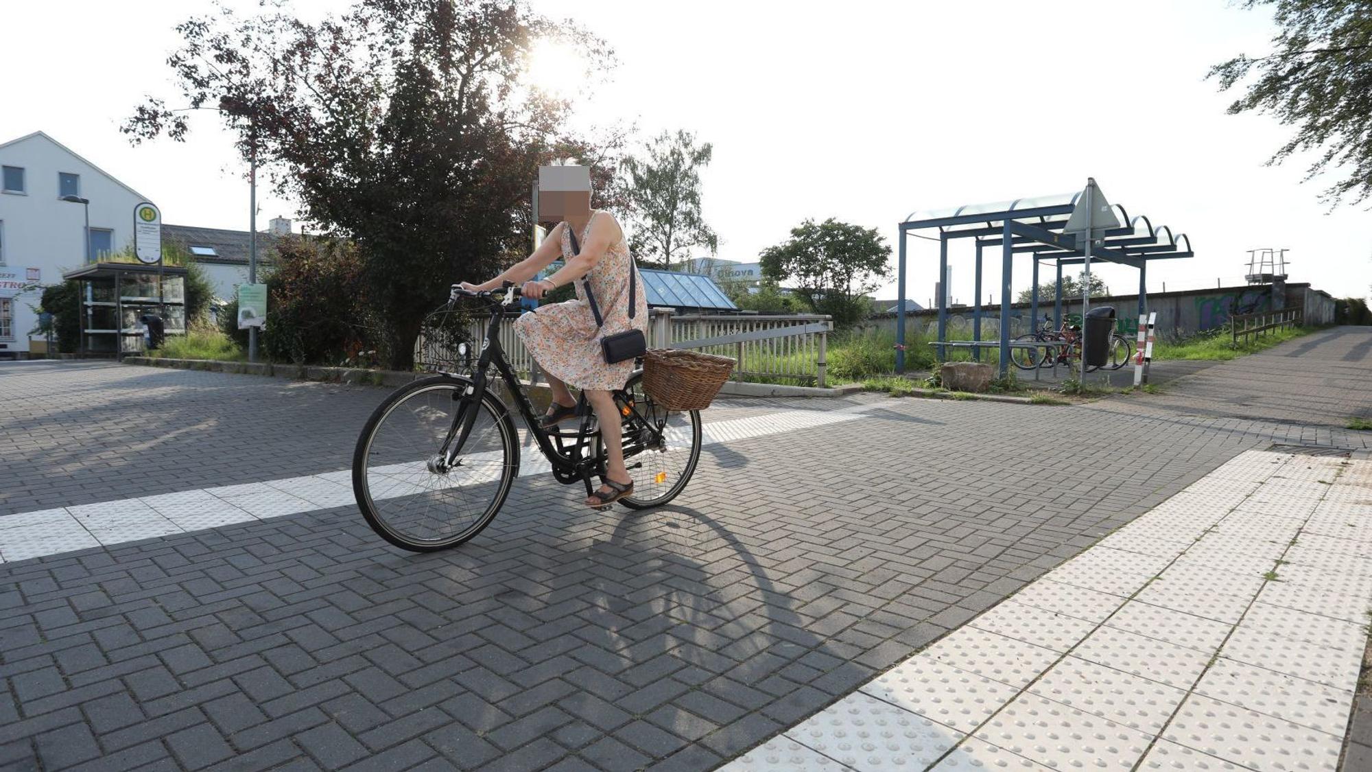 Eine Radfahrerin fährt auf einem Radweg, im Hintergrund steht eine Fahrradabstellanlage.