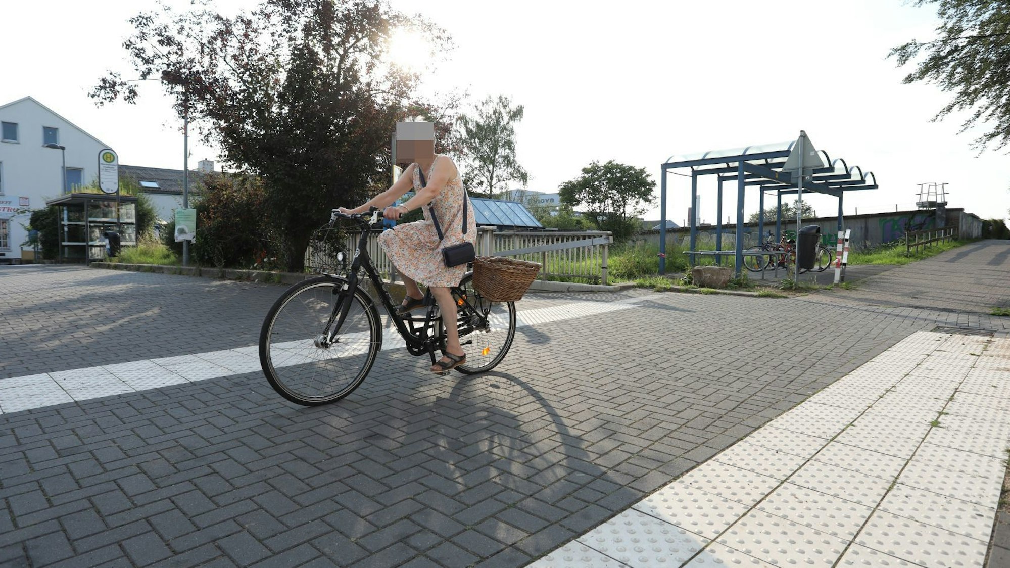 Eine Radfahrerin fährt auf einem Radweg, im Hintergrund steht eine Fahrradabstellanlage.
