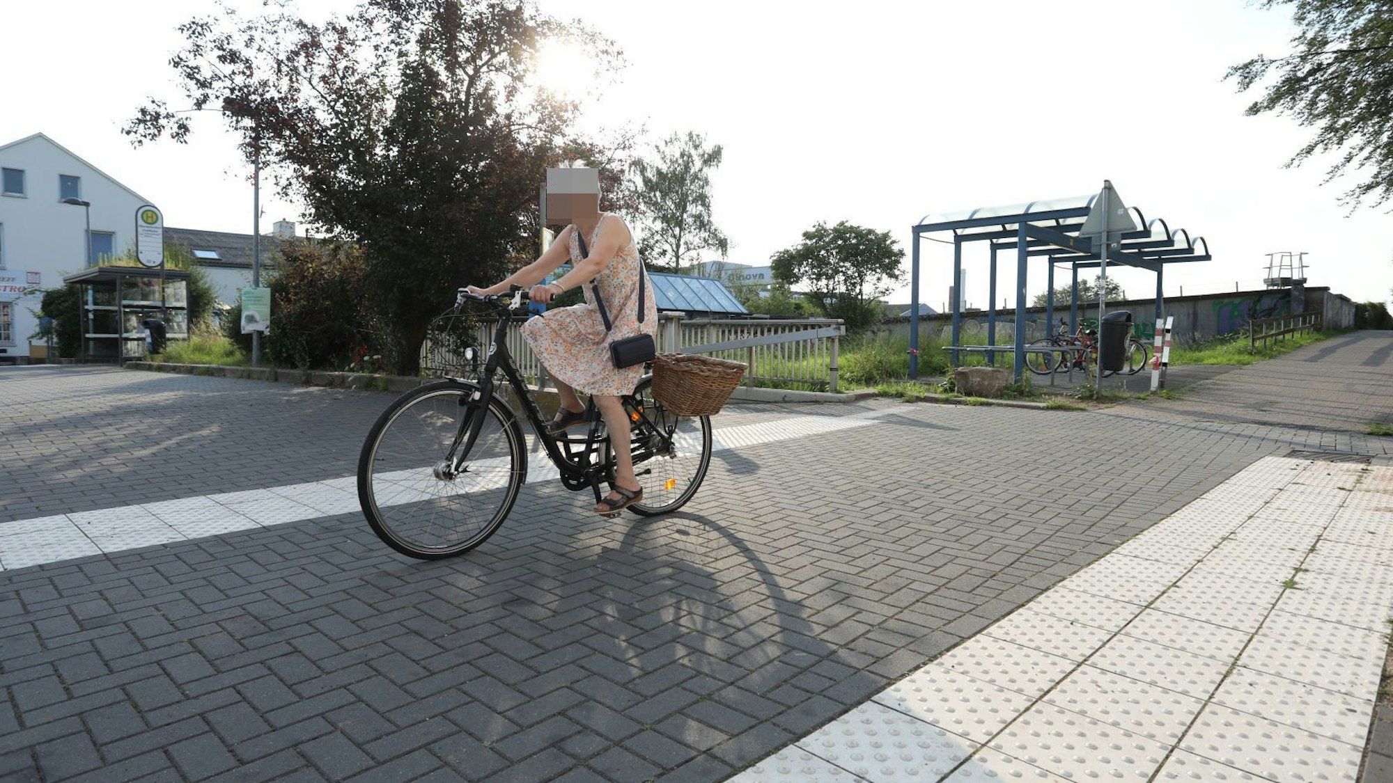 Eine Radfahrerin fährt auf einem Radweg, im Hintergrund steht eine Fahrradabstellanlage.