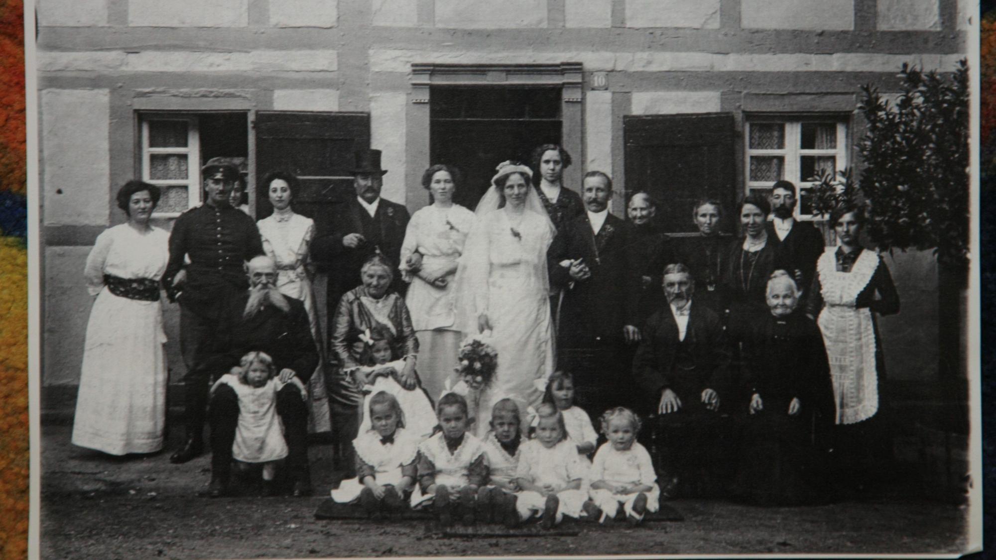 In drei Reihen aufgereiht stehen die Familienmitglieder anlässlich eines Hochzeitfotos.