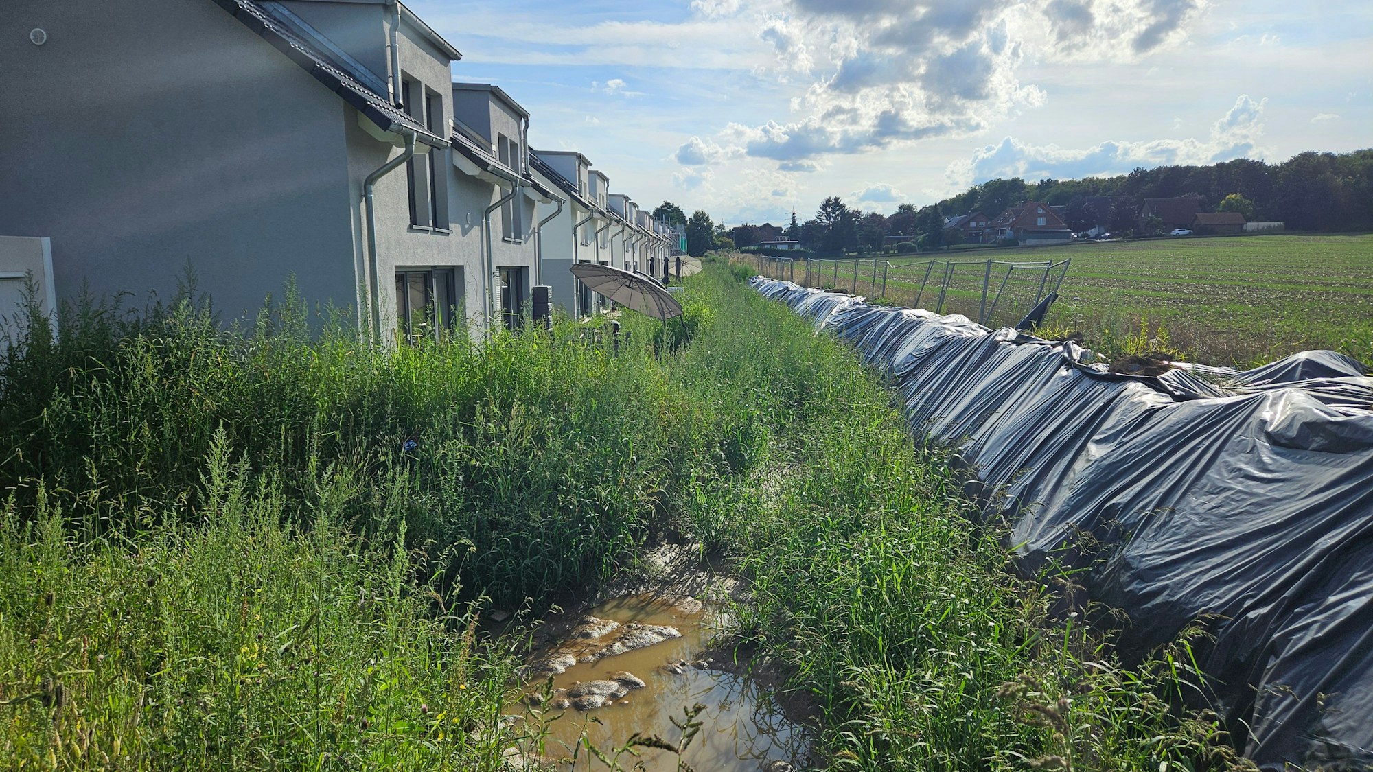Ein provisorischer Erdwall hält das Wasser von einem Acker ab und schützt Häuser.