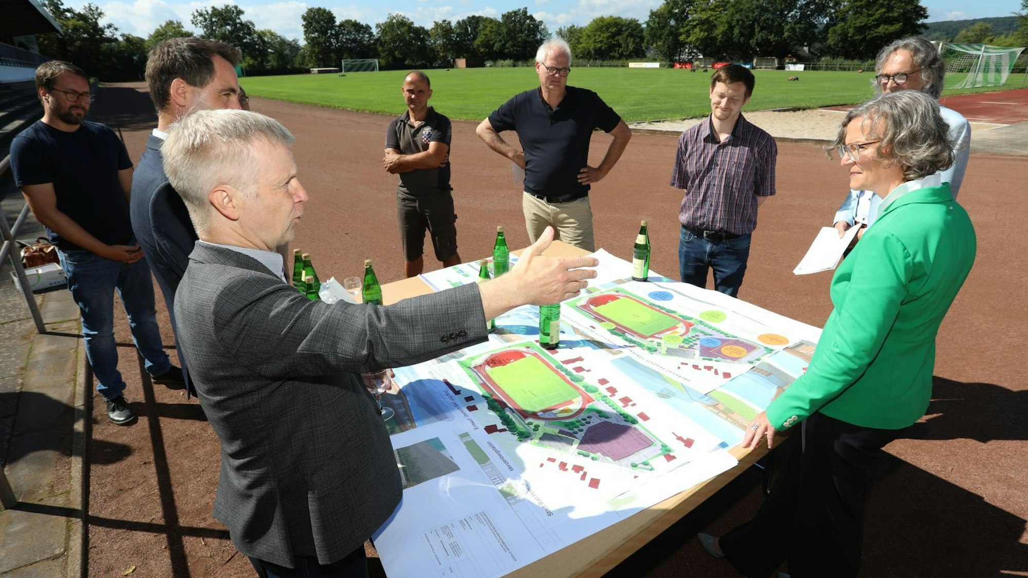 Eine Gruppe vor einem Tisch mit Plänen, der im Stadion aufgestellt wurde.