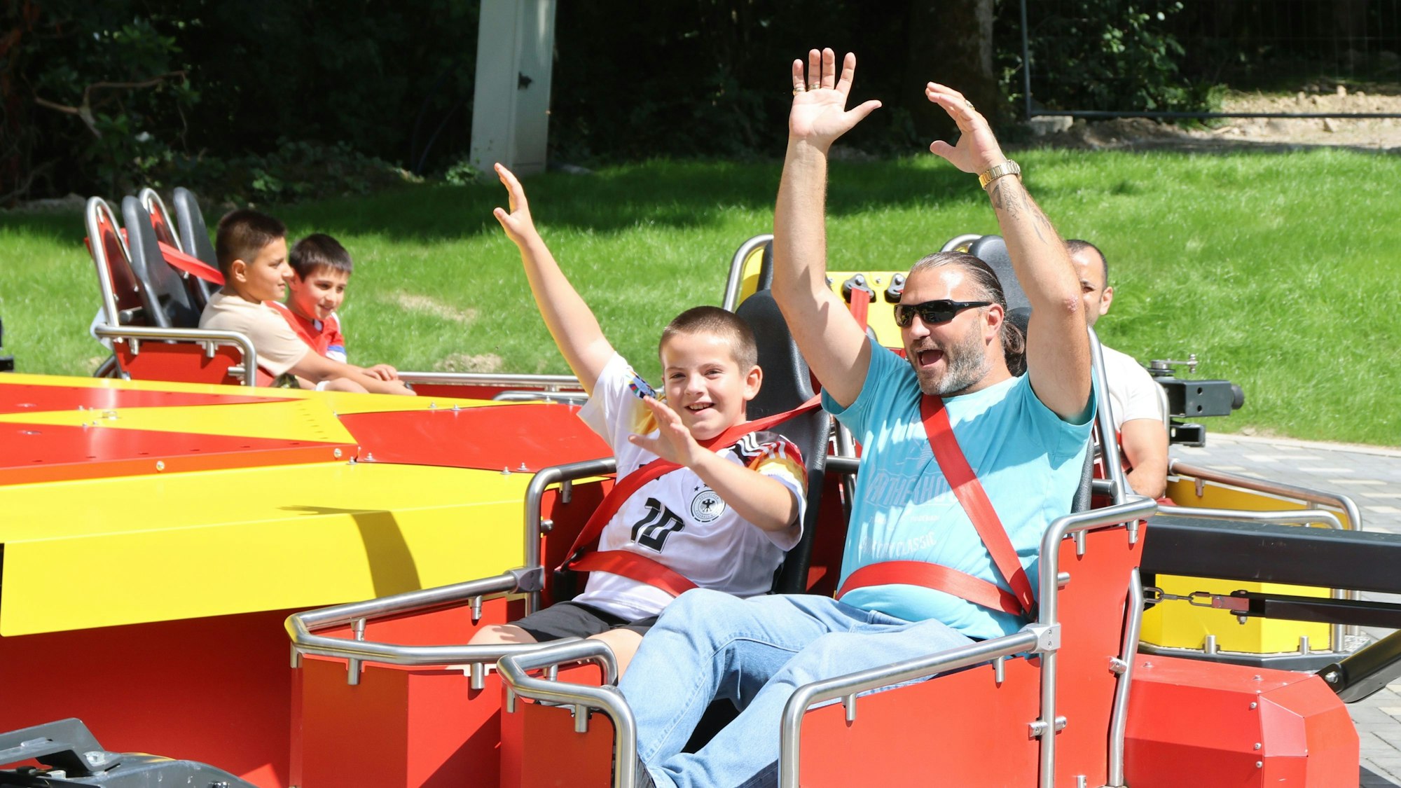Leute sitzen im Karussell und reißen die Arme zum Himmel.
