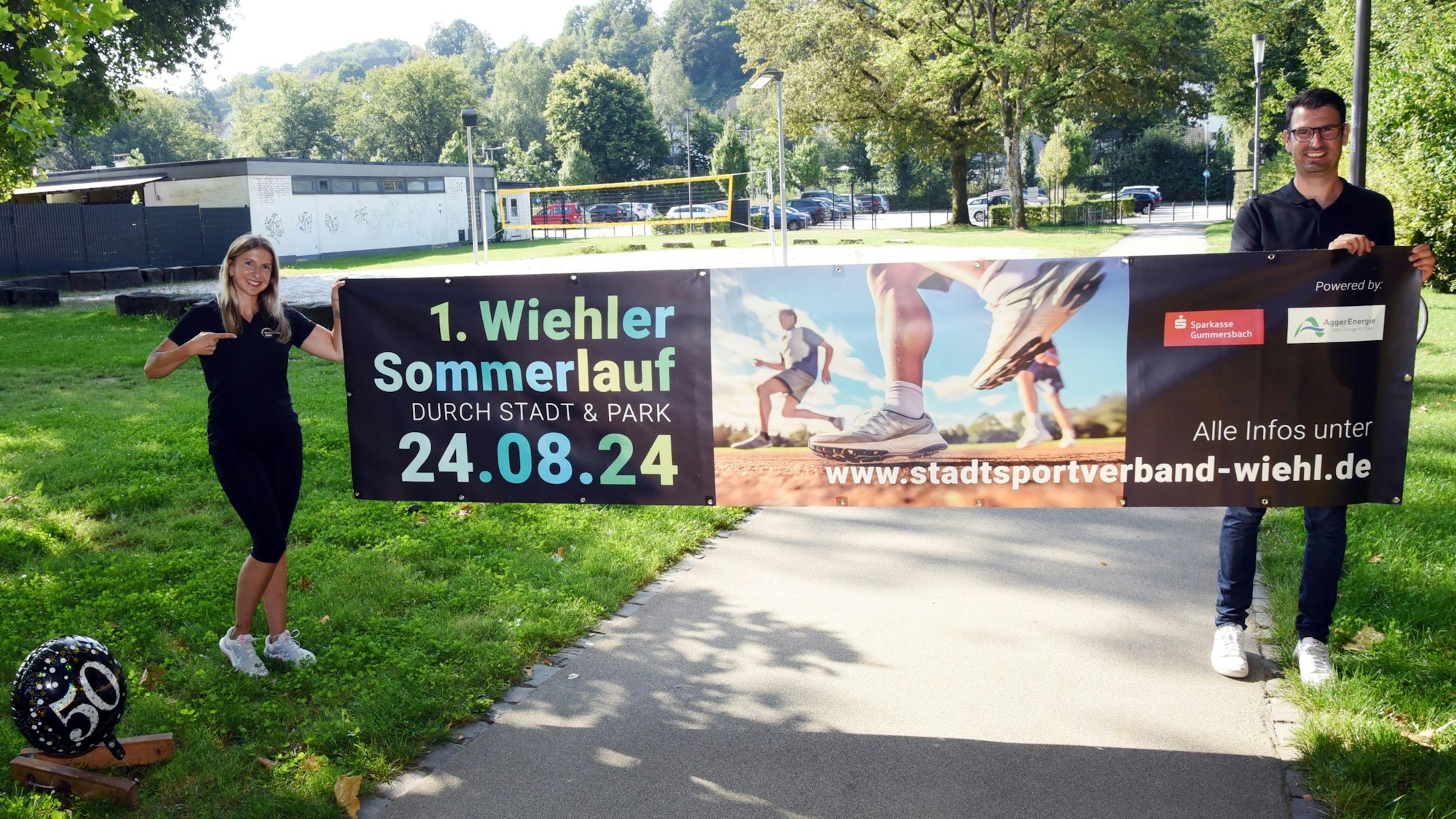 Eine Frau und ein Mann halten ein Werbebanner in die Höhe.