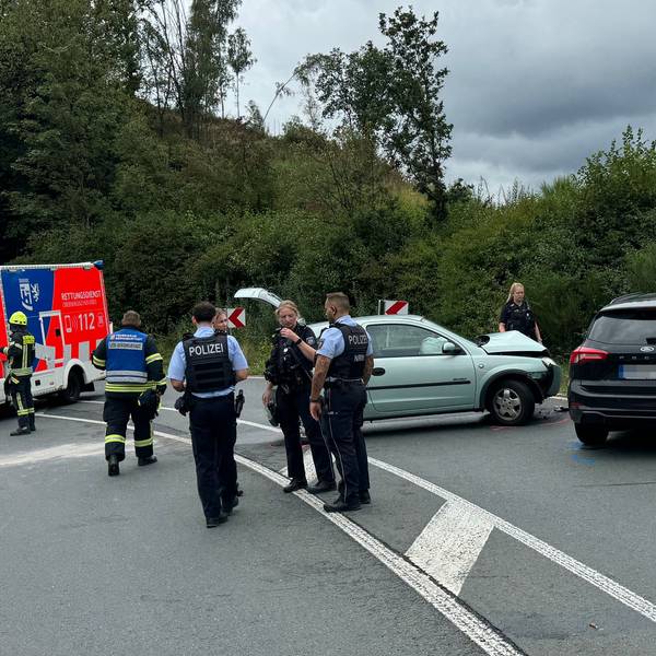 Das Foto zeigt eine Unfallstelle mit zwei beschädigten Autos, sowie Einsatzkräften von Polizei, Rettungsdienst und Feuerwehr.