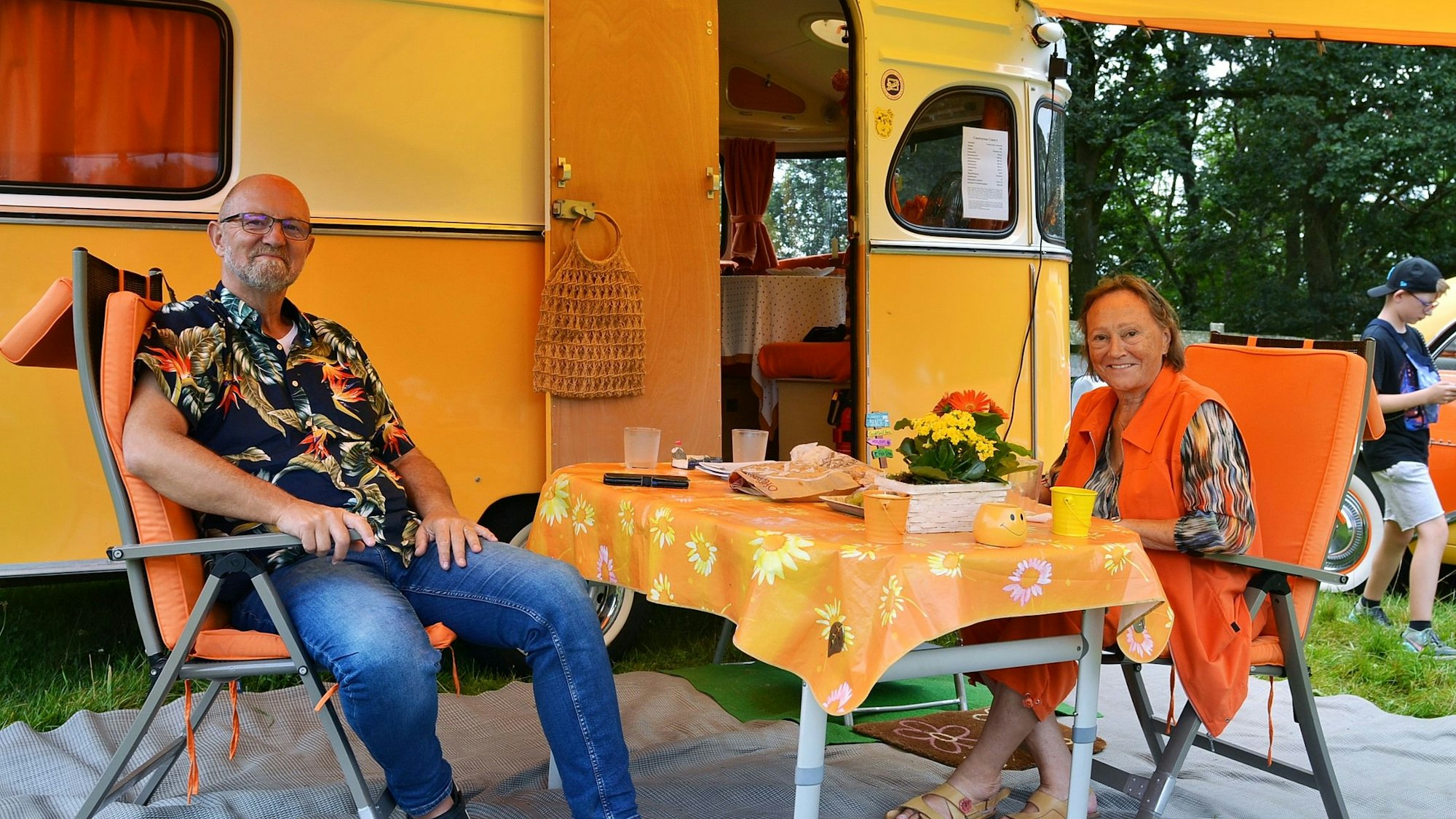 Hildegard und Thomas Hansen sitzen vor ihrem historischen Wohnwagen aus den 70er-Jahren.