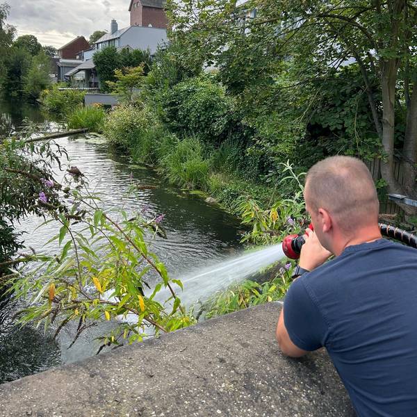 Ein Feuerwehrmann führt einem Gewässer Frischwasser zu.