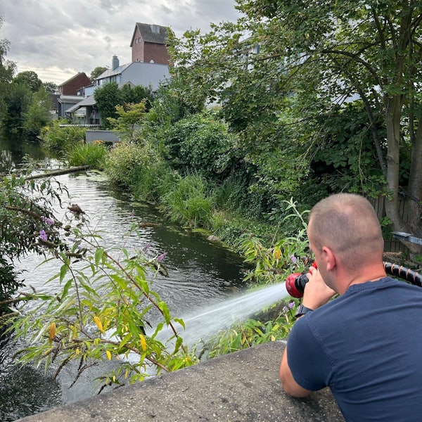 Ein Feuerwehrmann führt einem Gewässer Frischwasser zu.