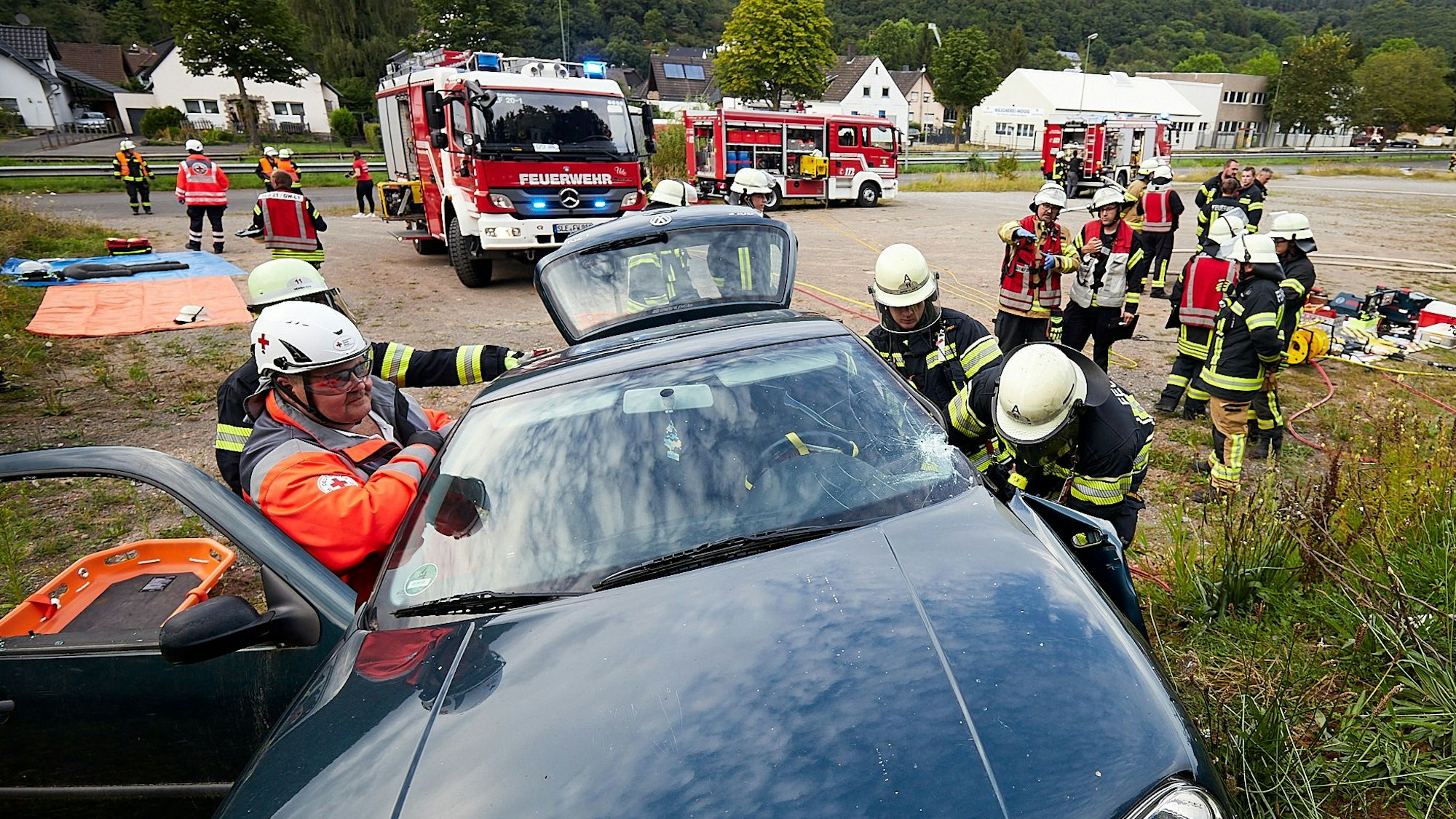Kräfte von DRK und Feuerwehr bei einer Großübung in Gemünd; im Vordergrund steht ein verunfalltes Auto.