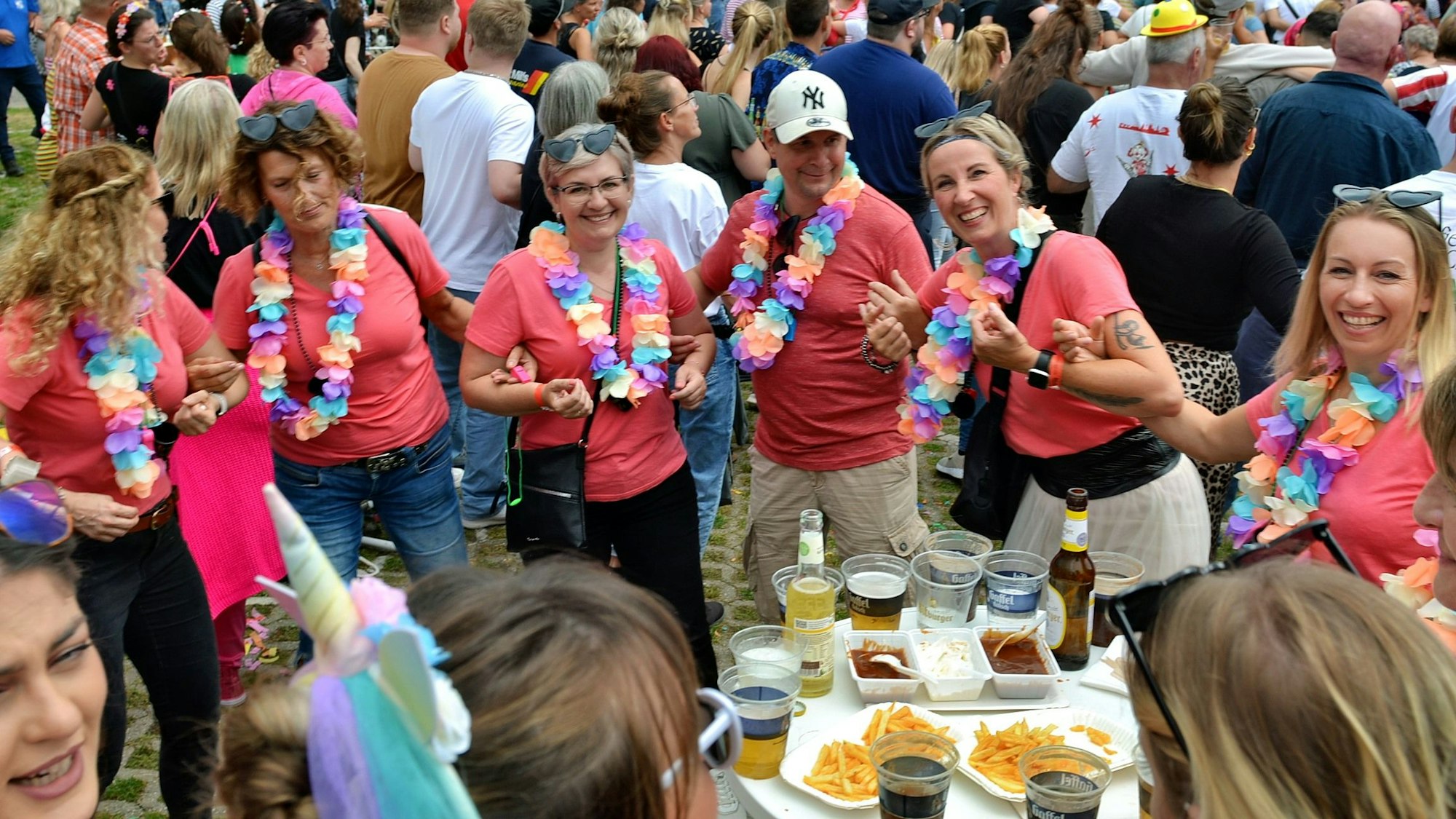 Eine Gruppe von Besucherinnen des Kölsch-Festivals am Firmenicher Zikkurat. Sie tragen rote Shirts und Blumenketten.