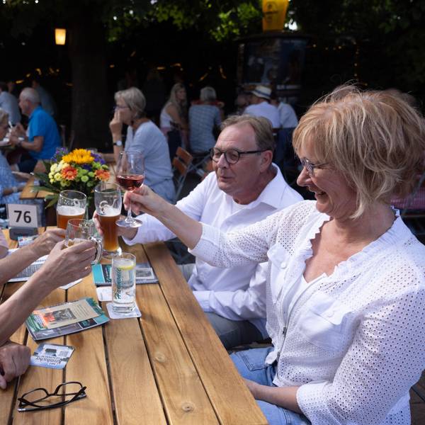 Eine Gruppe sitzt am Biertisch und protest sich zu.