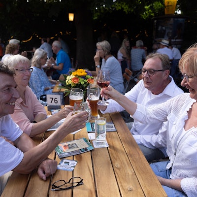 Eine Gruppe sitzt am Biertisch und protest sich zu.