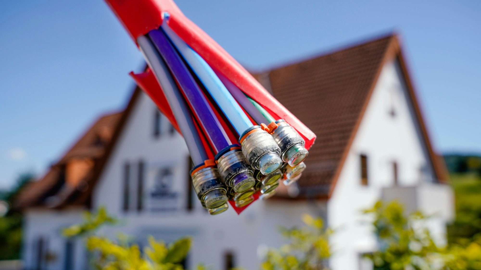 Ein Bündel mit Umhüllungen für Glasfaserkabel hängt vor einem Wohnhaus.