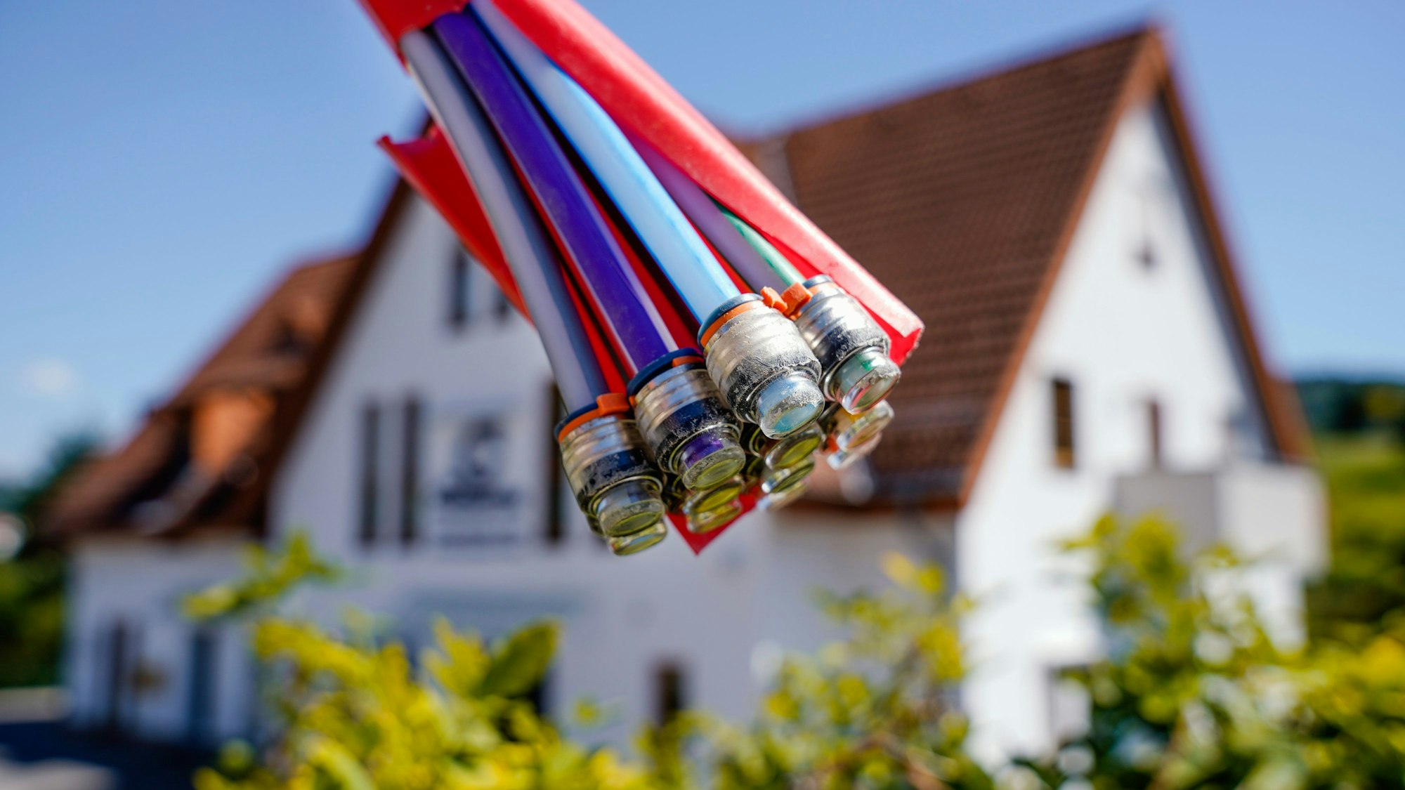 Ein Bündel mit Umhüllungen für Glasfaserkabel hängt vor einem Wohnhaus.