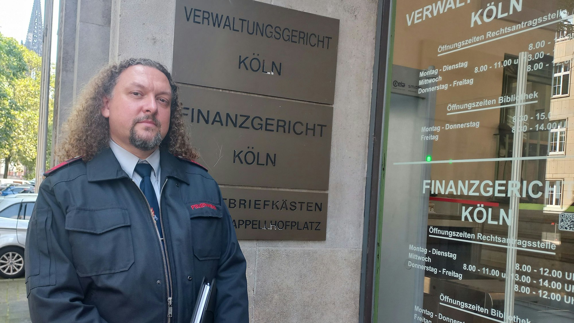 Zu sehen ist ein Feuerwehrmann vor dem Gebäude des Kölner Verwaltungsgerichts.