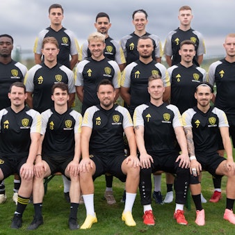 Der SC Germania Erftstadt-Lechenich hat sich für ein Mannschaftsfoto auf einem Rasen versammelt. Im Hintergrund ist der Himmel bewölkt.